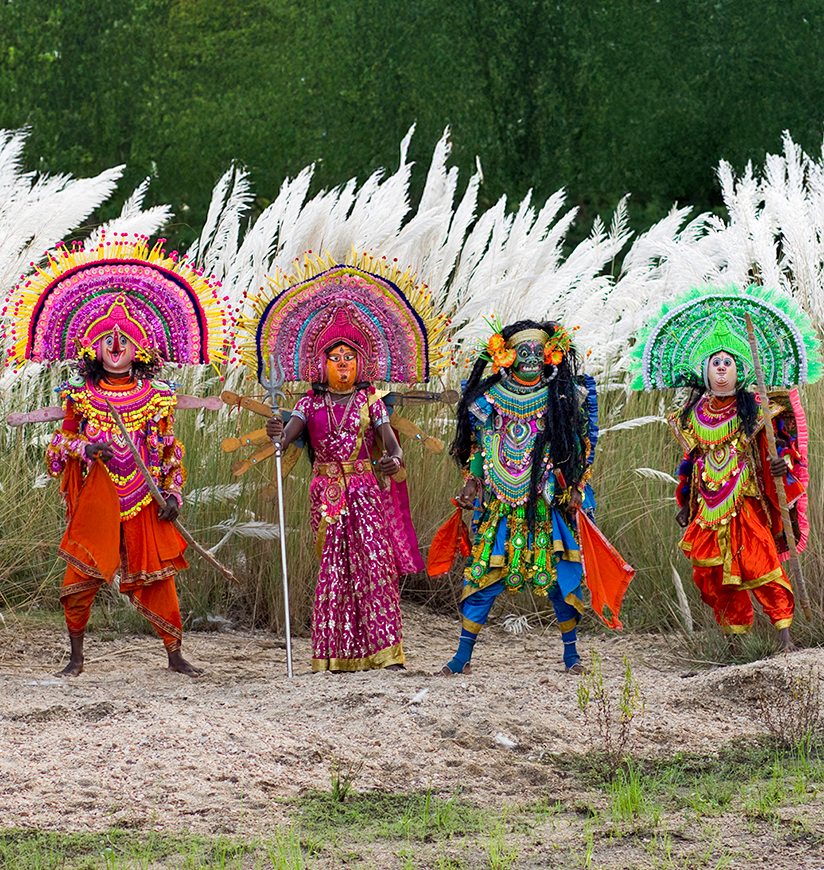 Chhau dancers performs Indian antient traditional regional famous religious acrobatic mask dances in open air at the river side full of Kanch grass or kash phool as open natural background in Purulia